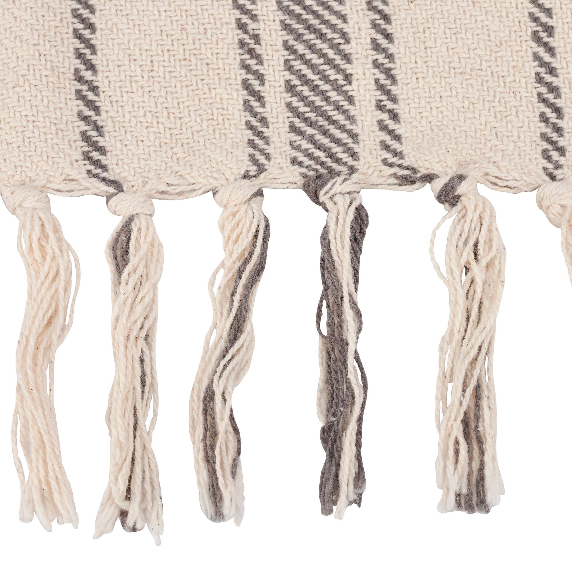 A beige and gray striped cotton throw blanket with tassels on the edges, folded and placed on a flat surface at the rustic barn in killingworth ct