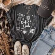 Dark gray t-shirt with 'Coffee Club' design, surrounded by coffee-themed items on a textured surface at the rustic barn in killingworth ct
