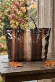Striped tote bag with 'TOTE BAG' text on a wooden surface with autumn leaves.