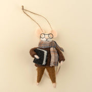 Felted animal ornament resembling a mouse wearing glasses, a scarf, and holding a book on a beige background at the rustic barn in killingworth ct