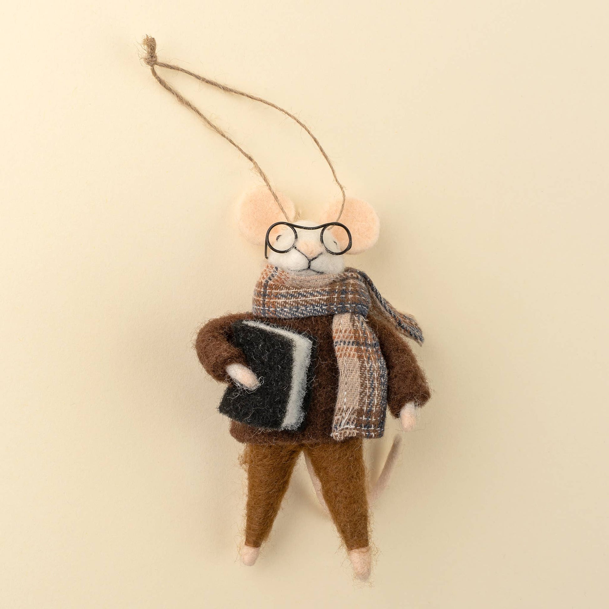 Felted animal ornament resembling a mouse wearing glasses, a scarf, and holding a book on a beige background at the rustic barn in killingworth ct
