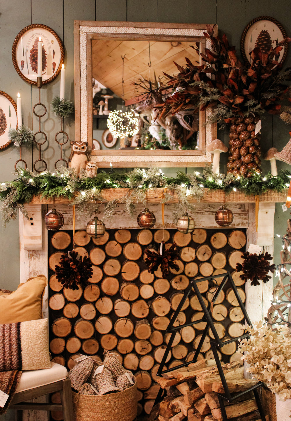 Beautiful christmas mantle setup with dark greens, evergreens, wooden textures, rich browns, cozy accents, warm blankets and pillows for your home decor. Gorgeous prints and mood lighting for the holiday Chistmas season. Home decor for sale at the Rustic Barn in Killingworth, CT