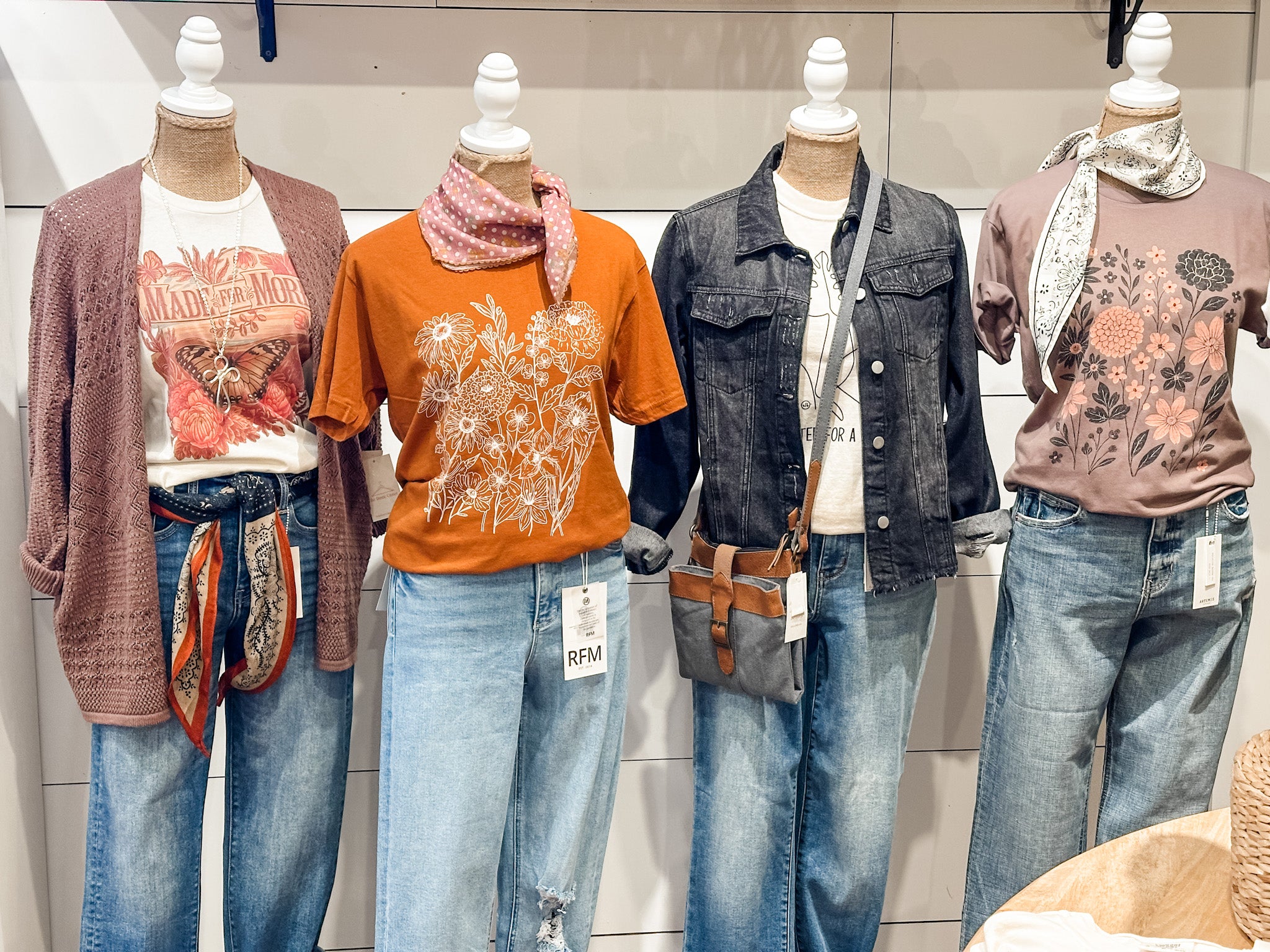 Mannequins wearing a variety of clothing items including shirts, jackets, and jeans in a store setting.