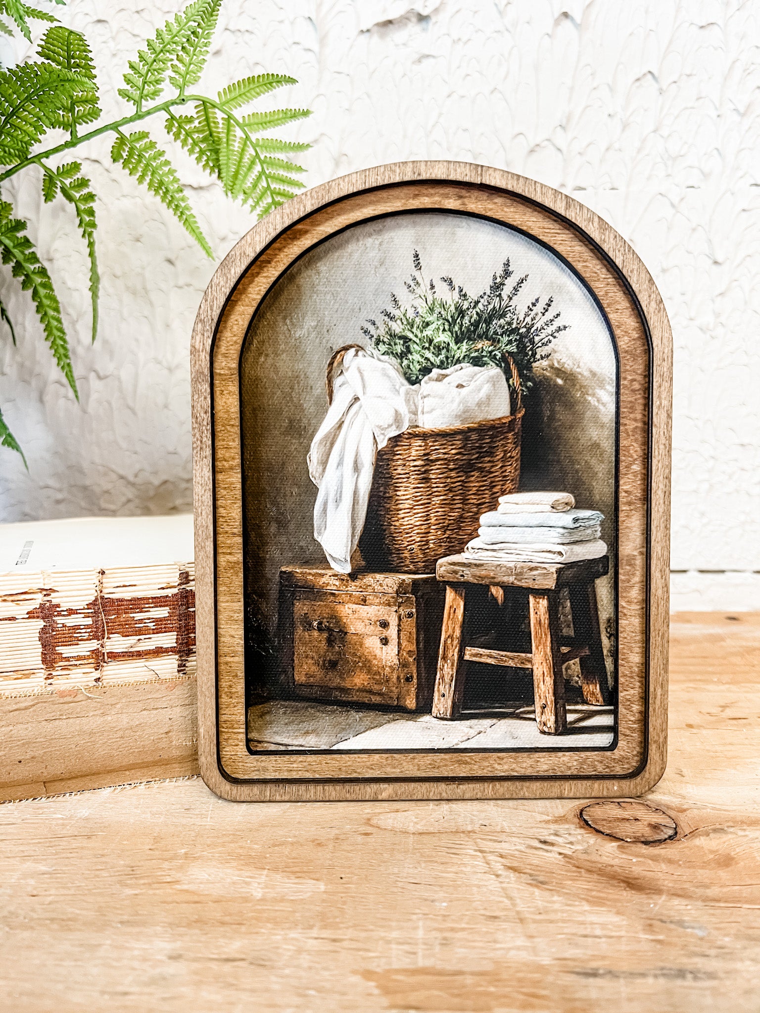 Decorative wooden frame with a small painting inside, featuring a basket and books on a wooden stool at the rustic barn in killingworth ct