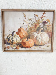 A framed still life painting featuring orange and white pumpkins with dried flowers and grasses, displayed on a textured white wall at the rustic barn in killingworth ct