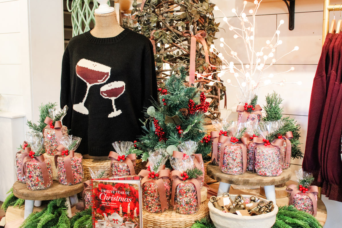 Super cozy fun christmas set up featuring a martini glass girls night out sweater, christmas cookbooks, christmas candles that are pre-wrapped for gifts, and gold candle snuffers with warm holdiday accents. All for sale at the rustic barn in Killingworth,CT