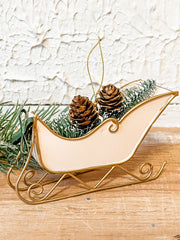 metal cream sleigh ornament with bottle brush trees in it at the rustic barn in Killingworth ct