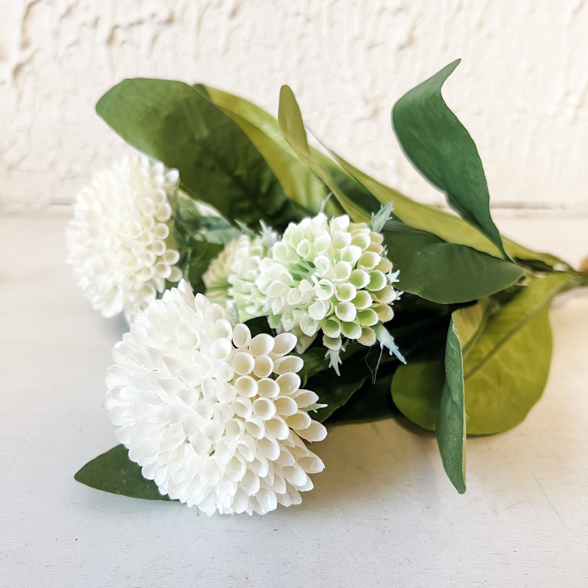 Bouquet of white flowers with green leaves on a light background